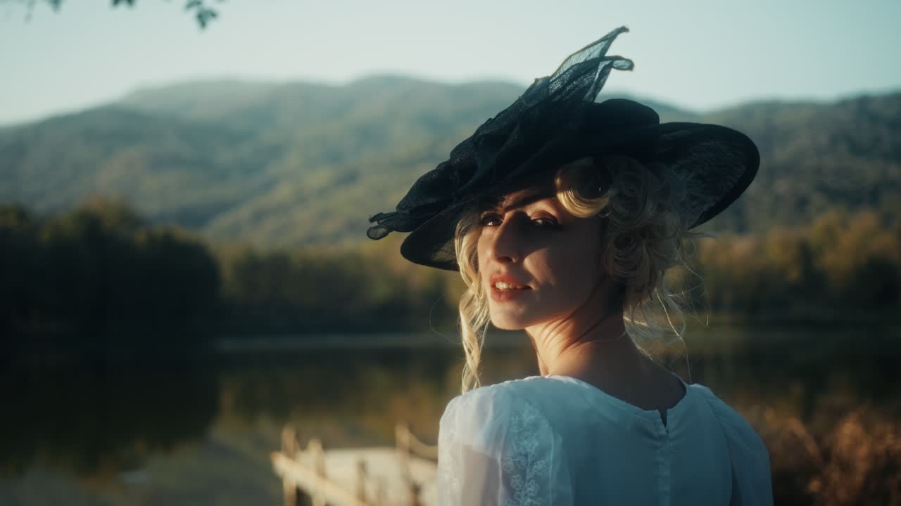 Donna elegante con abito e cappello vintage in riva a un lago sereno