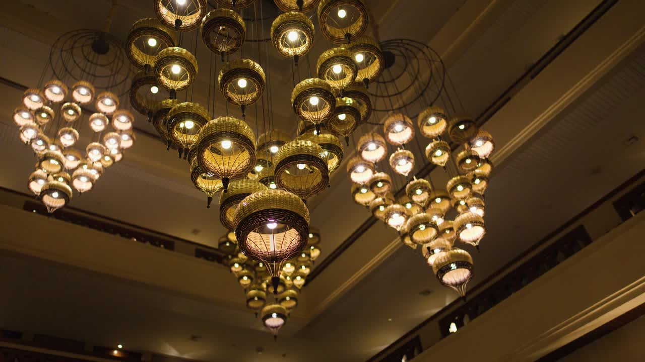 Warm chandelier lights illuminate traditional Thai decor in a luxury Bangkok hotel lobby interior