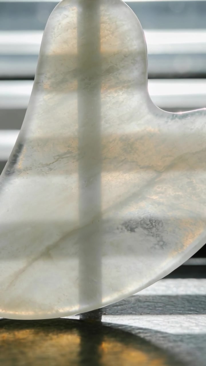 Vertical video: Shifting sun through blinds revealing heart stone showing warm veins on sill, peg