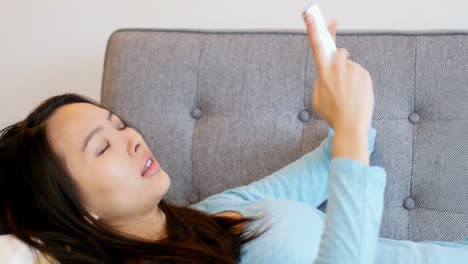Beautiful-woman-relaxing-on-sofa-and-using-mobile-phone