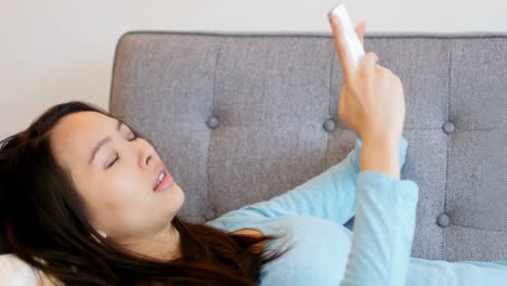 소파에서 휴식을 취하고 휴대전화를 사용하는 아름다운 여성