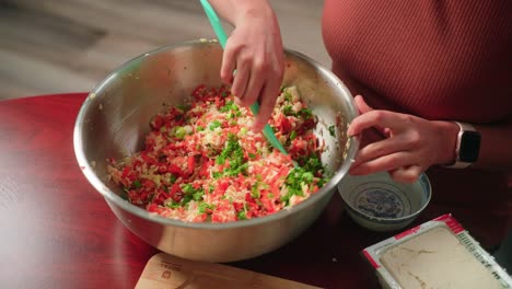 women mixing vegetables in large bowl