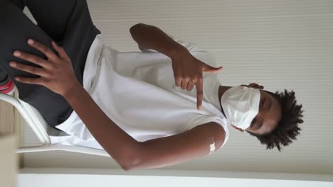 vertical video of african teenager showing covid-19 vaccine bandage merrily