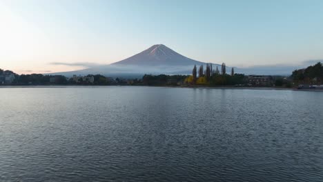 aerial view low over lake kawaguchi, toward mount fuji, foggy, fall morning in japan