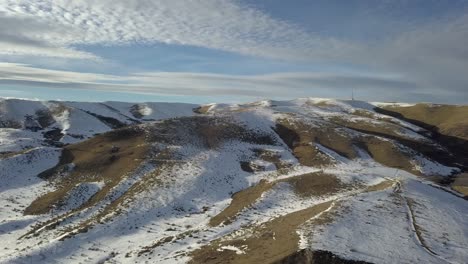 An-aerial-pan-over-a-snow-spotted-mountain