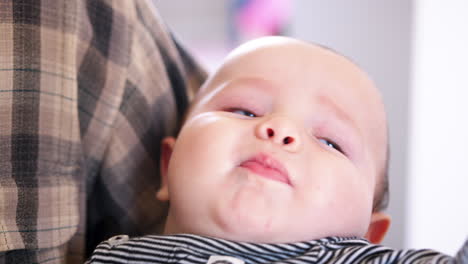 close up of baby grandson being cuddled by grandfather