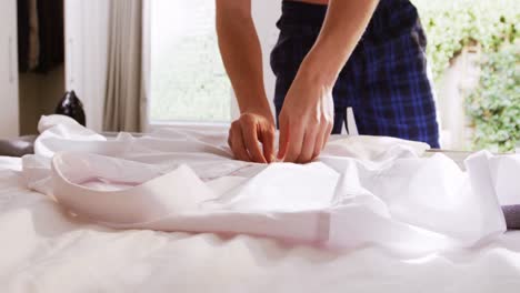 man unbuttoning his white shirt in bedroom