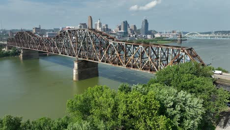 aerial reveal of old bridges on ohio river with cincinnati skyline in distance