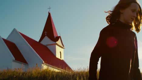 handheld shot of a girl in iceland walking in front of a church at sunset