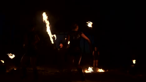 professional fire show in the old hangar of the aircraft show professional circus artists three women in leather suits and a man with two flamethrowers.