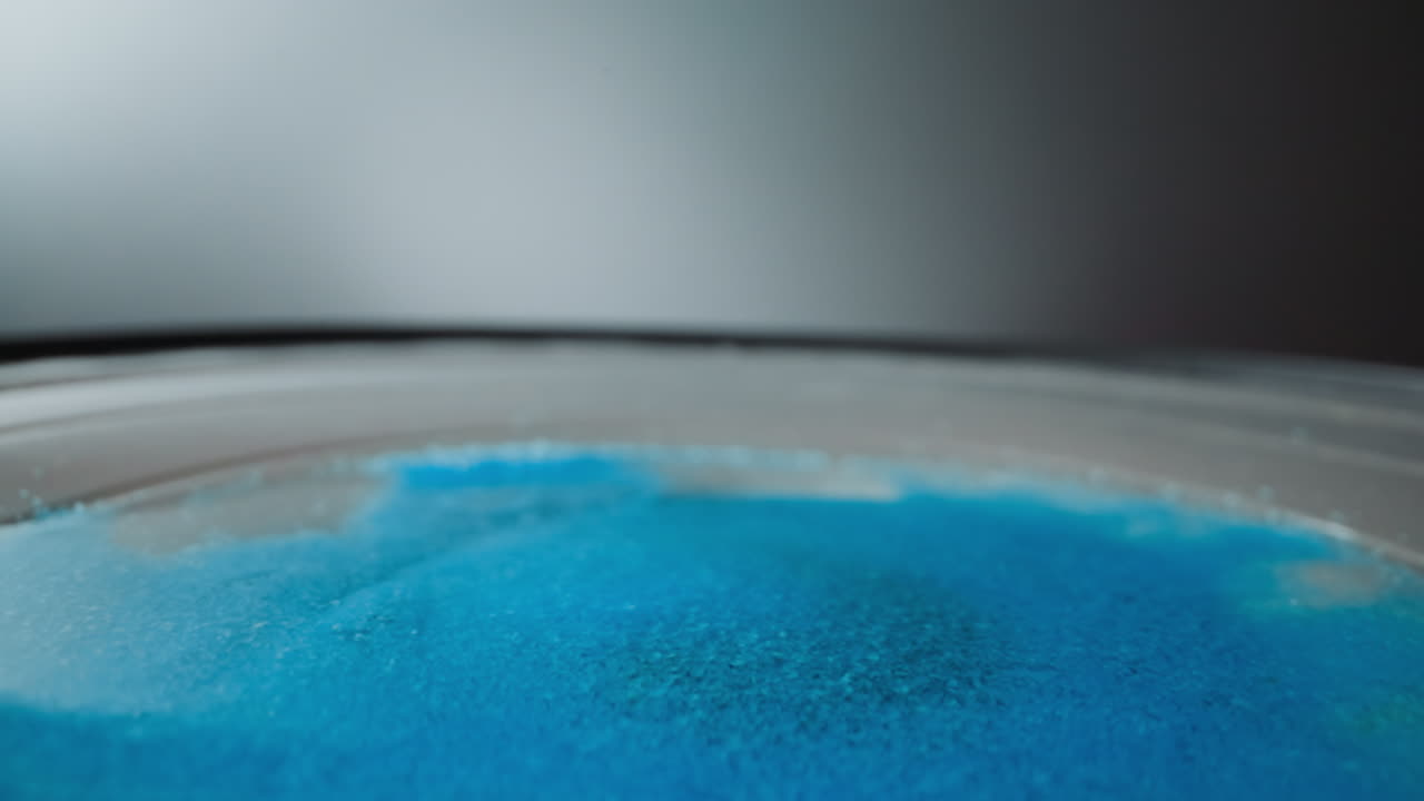 밝은 파란색 모래  ⁇ 어리는 구부러진 둥근 표면에 있습니다.