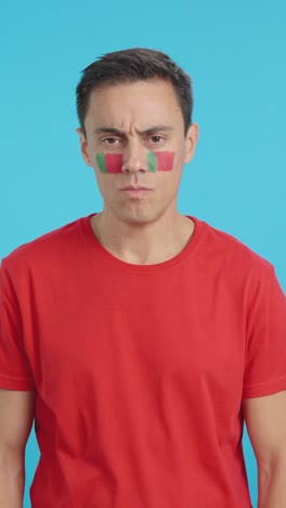 dignified and serious man with portuguese flag painted on face