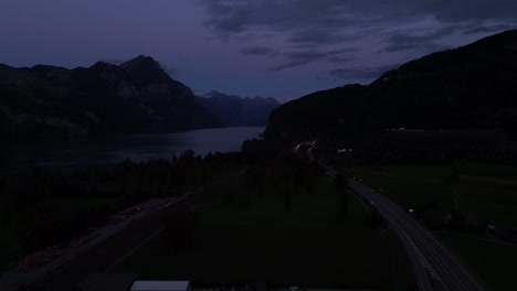 nighttime aerial view of a highway with flowing traffic near lake walensee, switzerland, surrounded by calm waters offering a tranquil evening ambiance.