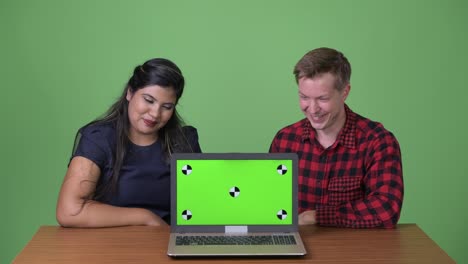 joven pareja de negocios multiétnica juntos contra un fondo verde