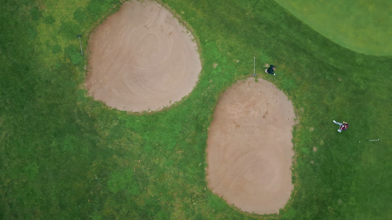 Top golf players walking green field with sand bunkers. Golfers preparing play