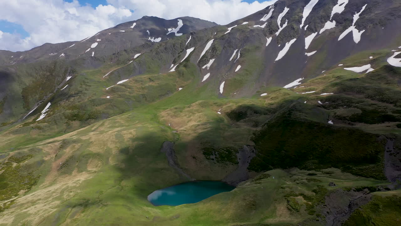 amplia toma cinematográfica de drones del lago oreit en tusheti, georgia, con sombras de nubes moviéndose a través de las montañas del cáucaso