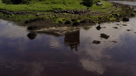 dynamic aerial shot scans dunguaire castle from a reflection on the water to its real top