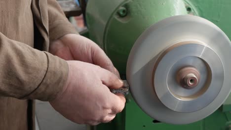 el trabajo en el molinillo de pedestal, la producción de artículos, el acabado de las piezas metálicas en la fábrica