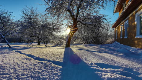 Puesta-De-Sol-De-Lapso-De-Tiempo-Sobre-Una-Casa-De-Campo-Con-Un-Huerto-Adyacente-Cubierto-De-Nieve