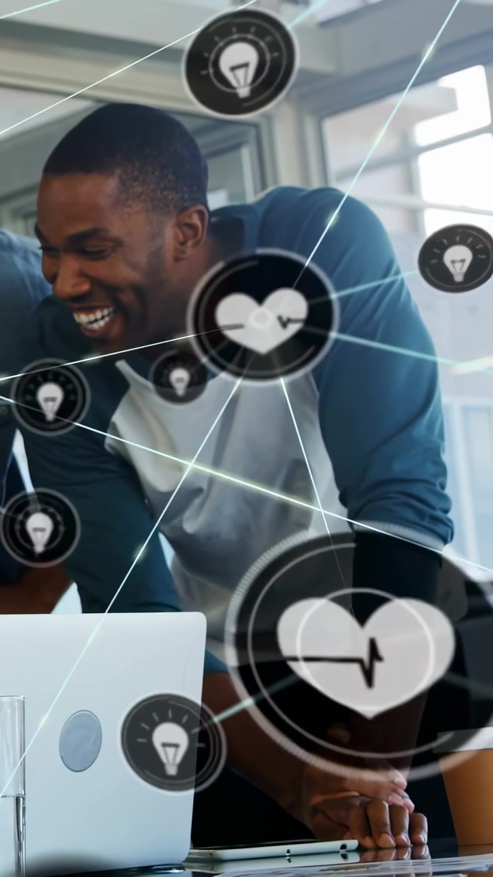 Vertical video: Man leaning over laptop while icons animating over laptop, showing ideas for tech
