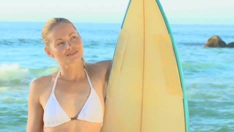 beautiful blonde woman posing with her surfboard