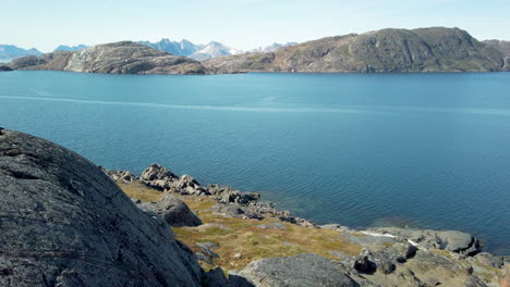 scenic view of rocky shoreline along coast of greenland from top of rocks lining the beach