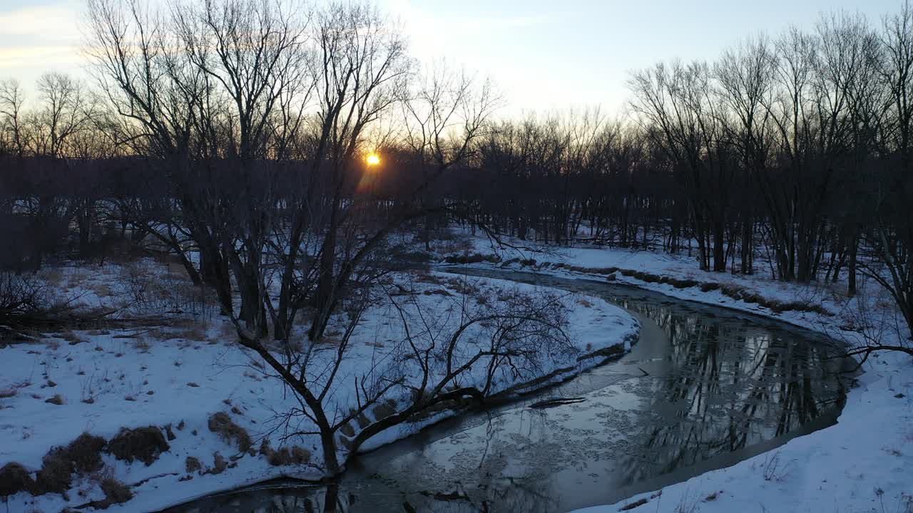 O pôr-do-sol de inverno sobre um riacho congelado
