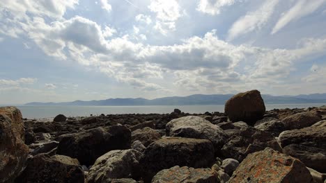 Bunter-Felsiger-Strand-Felsbrocken-Zeitraffer-Berglandschaft-Schnell-Inspirierende-Wolken-Ziehen-Vorbei