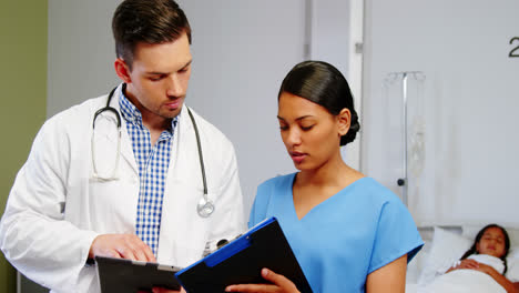 nurse and doctor discussing over clipboard