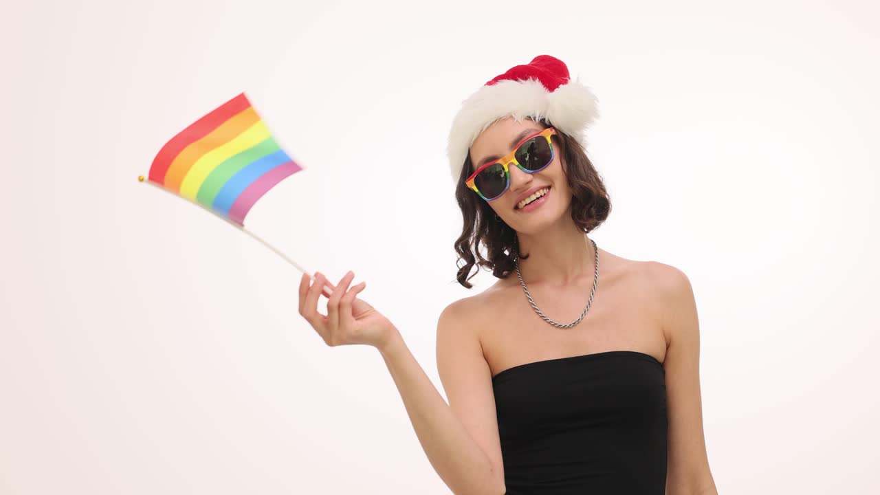 Young Woman in Santa Hat and Rainbow Sunglasses Holding Pride Flag