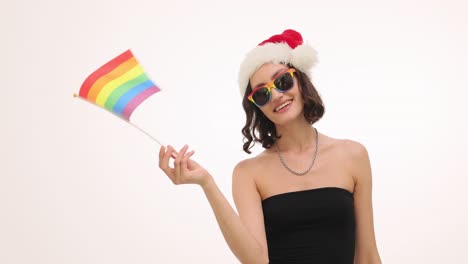 young woman in santa hat and rainbow sunglasses holding pride flag