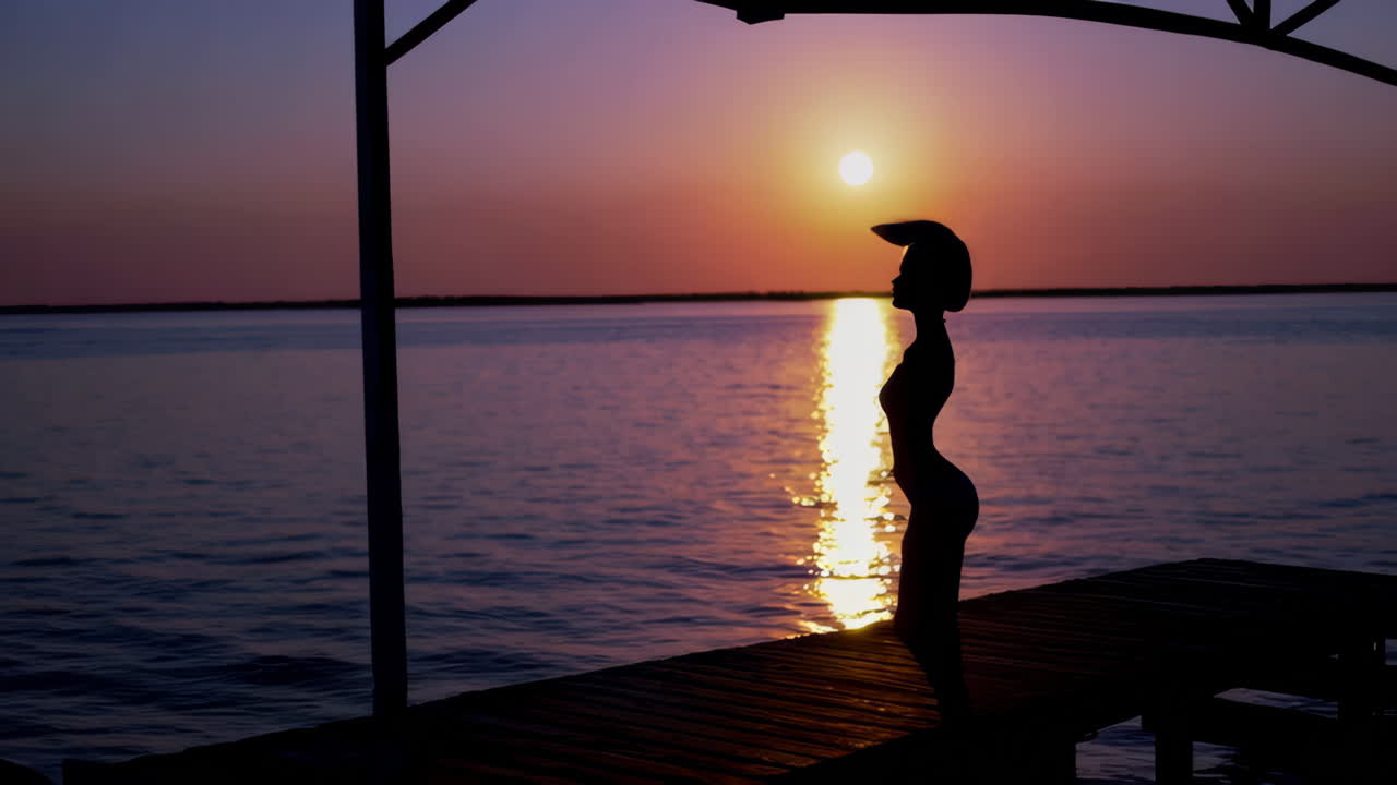 Silhouette of a Woman at Sunset on a Lakeside Pier