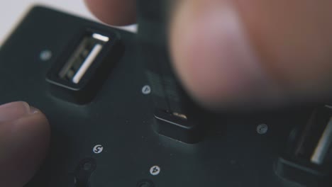 young man plugs usb cable in black hub on white background