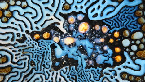 swirling patterns of blue, black, and gold as liquids interact and create an organic abstract design