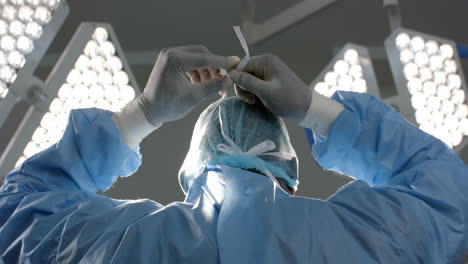 african american female surgeon wearing face mask in operating theatre, slow motion