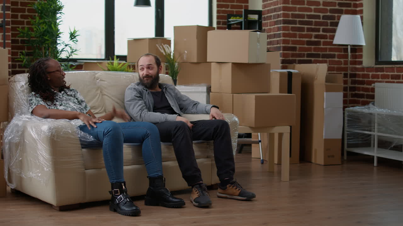 Couple sitting on living room couch and talking about decorations