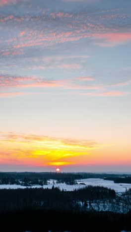 vertical winter morning sunrise hyperlapse. aerial drone timelapse in snow covered winter landscape. golden winter sunset over snow-covered landscape and forest.