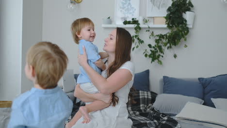 mom in a dress sitting on diwanie hugging her son