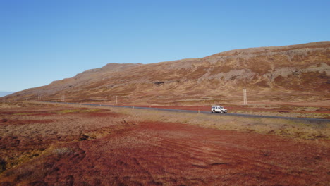 land rover defender conduciendo a través del paisaje interior de islandia rodeado de follaje otoñal rojo anaranjado