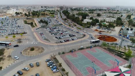 take drone aerial over a parking area and basketball courts.