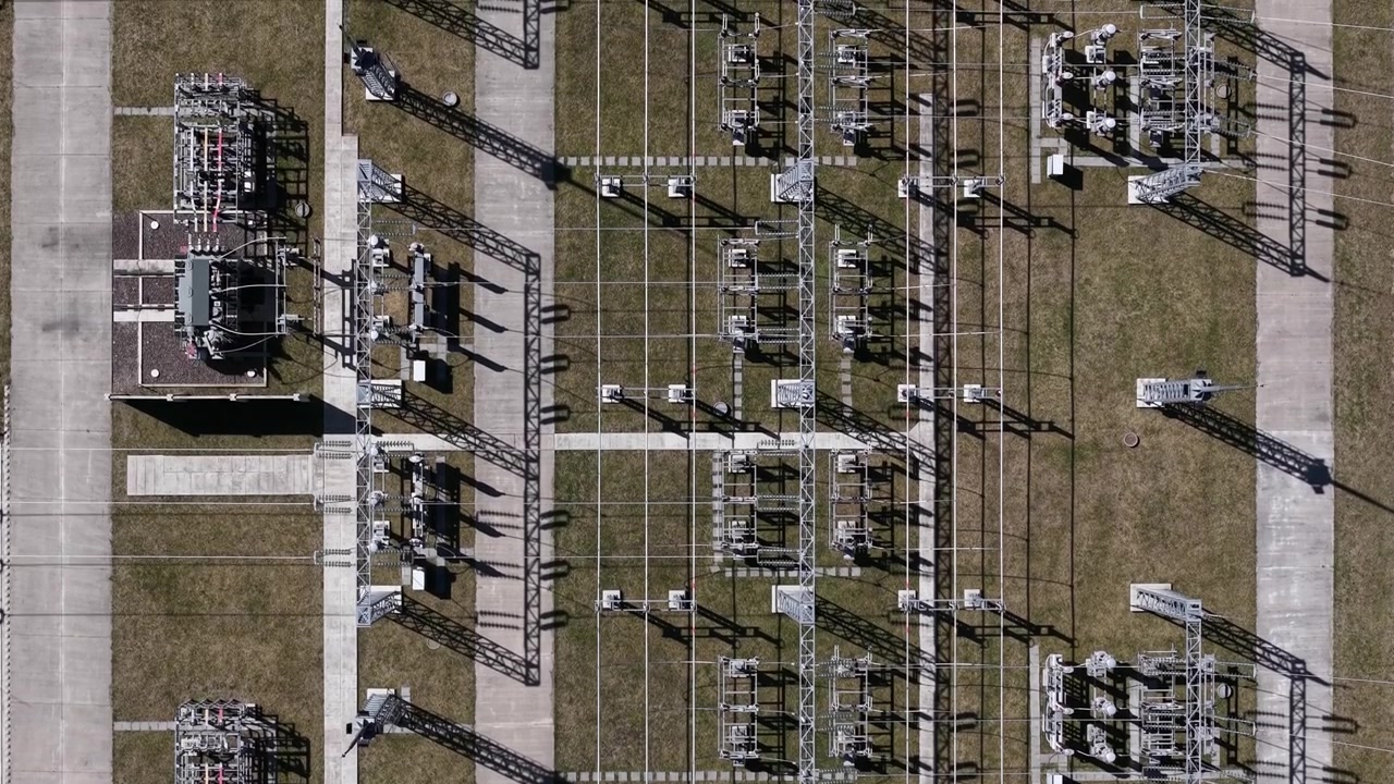 Letecký pohled shora ukazuje složité geometrické uspořádání vysokonapěťové elektrické rozvodny, která distribuuje energii po celé síti.