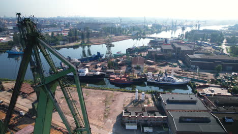 aerial view passing large green port cranes to reveal gdansk shipyard, poland