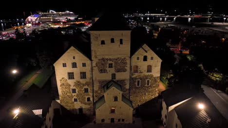 aerial orbit shot around the illuminated turku castle, nighttime in abo, finland