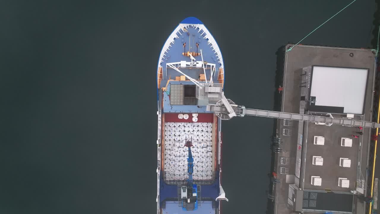 vista de arriba hacia abajo del buque de carga descargando pescado en faskrudsfjordur, este de islandia - toma aérea de drones