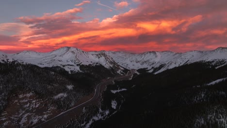 rocky mountains aerial drone i70 highway winter solstice colorado vibrant orange red cloudy skies setting sunset cars trucks traffic coon hill parshall eisenhower tunnel continental divide pan forward