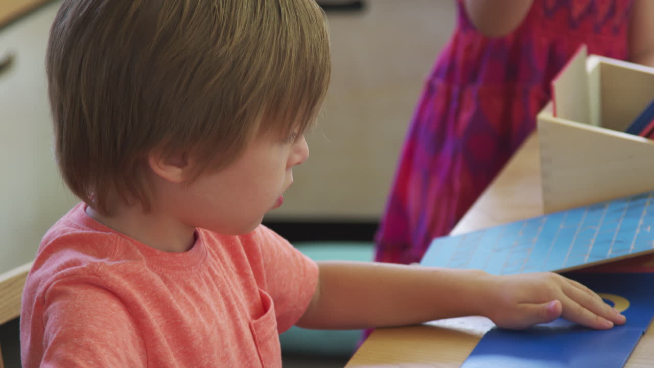 Alumno Montessori trabajando en un escritorio con letras en formas de madera.