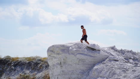man on a top of a mountain. young man standing on cliffs edge of top of the mountain