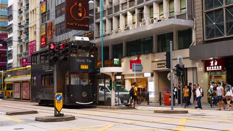 people crossing street with tram and bus nearby