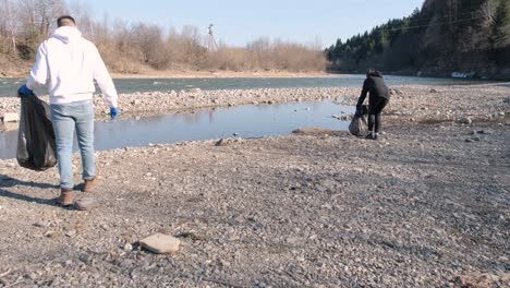 teamwork cleaning plastic on the beach. volunteers collect trash in a trash bag. plastic pollution and environmental problem concept. voluntary cleaning of nature from plastic. greening the planet