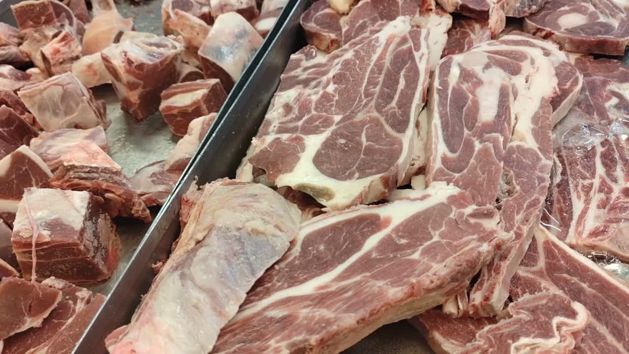 Slices of frozen beef neatly arranged on a tray in a supermarket. Ready for purchase, the meat is displayed under bright lighting, emphasizing its freshness and quality.